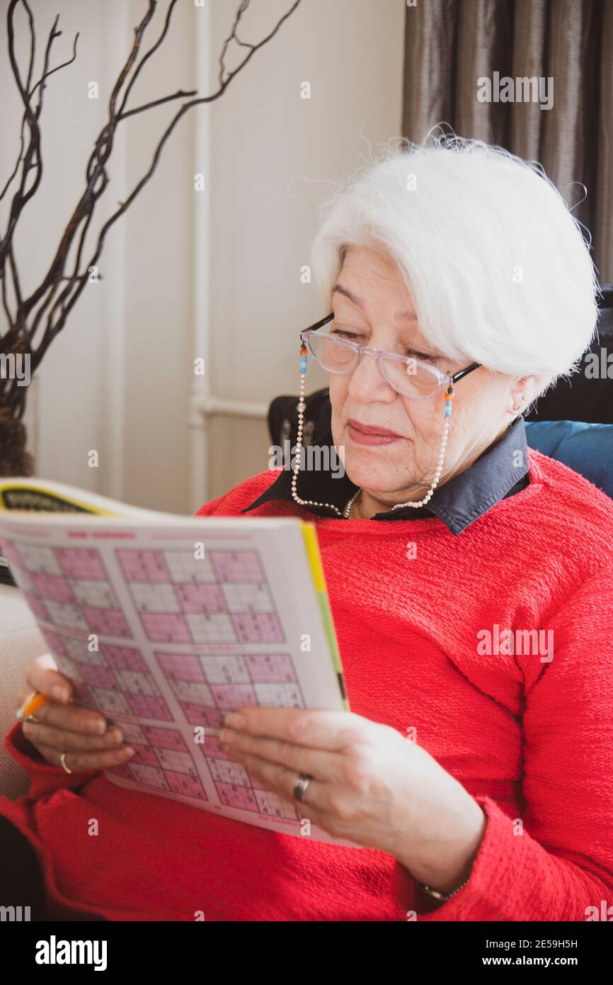 femme en chandail rouge assis sur un canapé blanc, a eu de mauvaises nouvelles au téléphone Banque D'Images
