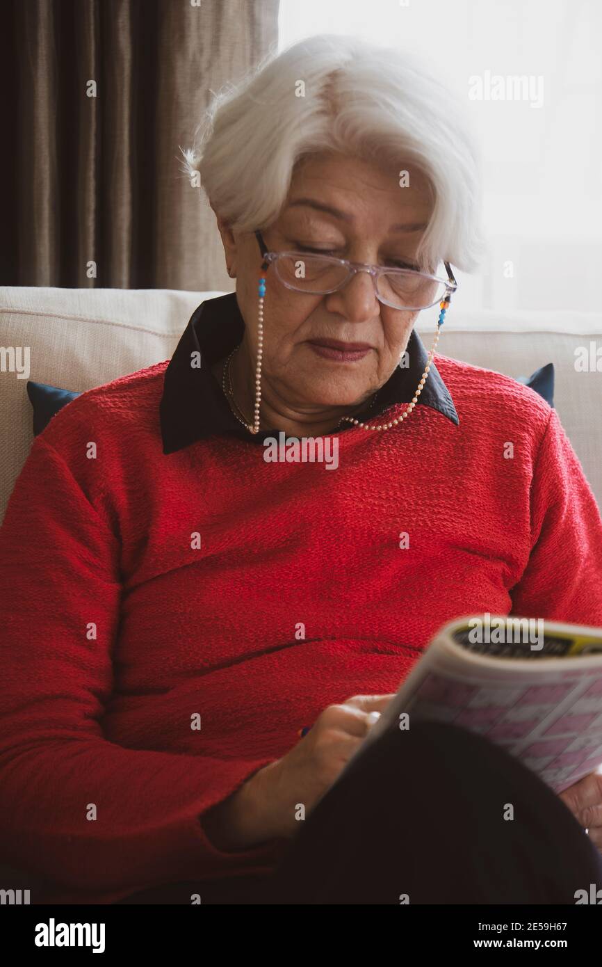 femme en chandail rouge assis sur un canapé blanc, a eu de mauvaises nouvelles au téléphone Banque D'Images
