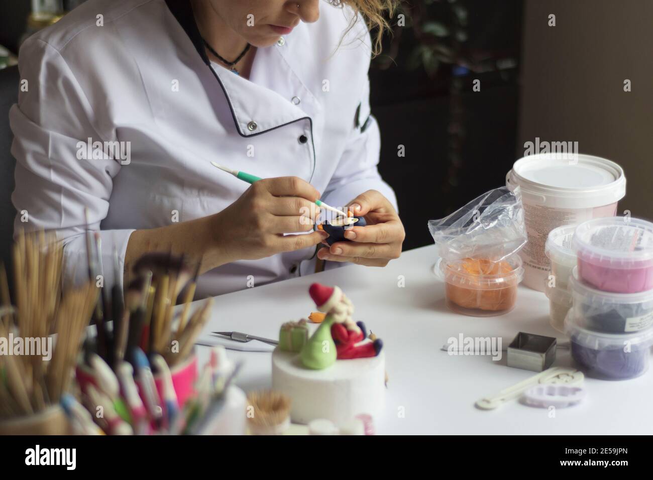 Processus de décoration de gâteau. Baker utilise des outils pour sculpter des motifs fondants : art comestible, design de gâteau, décoration de gâteau. Mise au point sélective des outils frontaux et de la main Banque D'Images