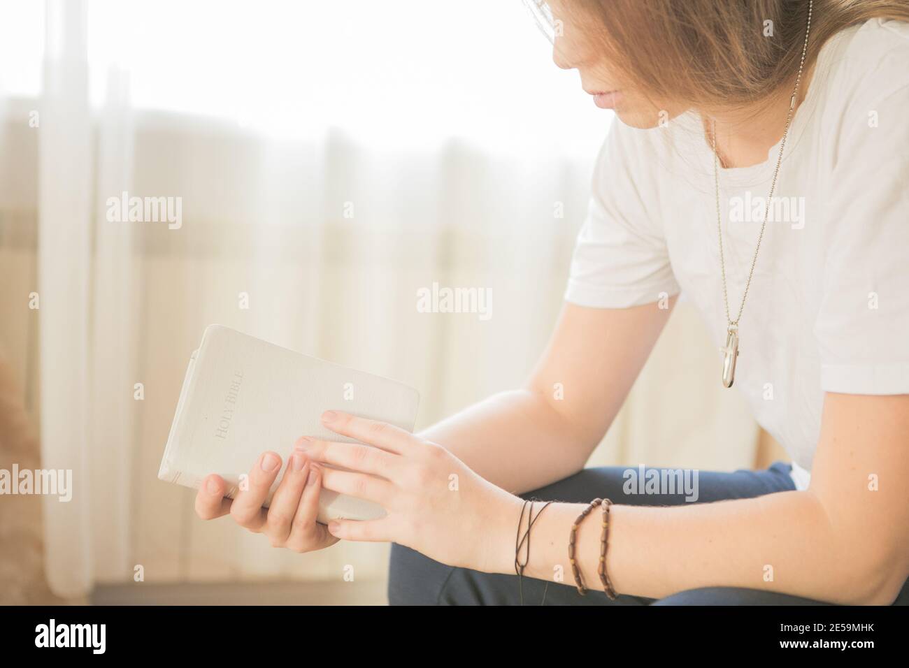 Les mains pliées dans la prière sur une Sainte Bible dans le concept d'église pour la foi, la spiritualité et la religion, la femme priant sur la sainte bible le matin. Banque D'Images
