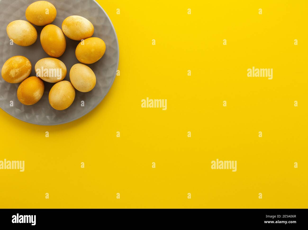 Oeufs peints en or de Pâques dans une assiette grise sur fond jaune, concept de fête de pâques Banque D'Images