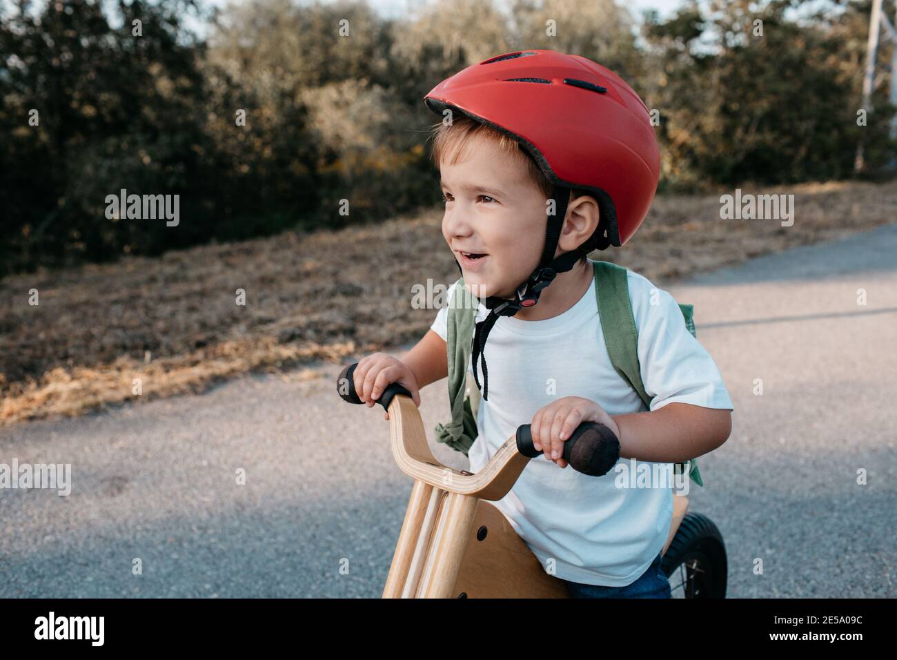 Enfant heureux portant un casque de vélo. Un jeune garçon souriant qui fait du vélo d'équilibre un soir d'été. Banque D'Images