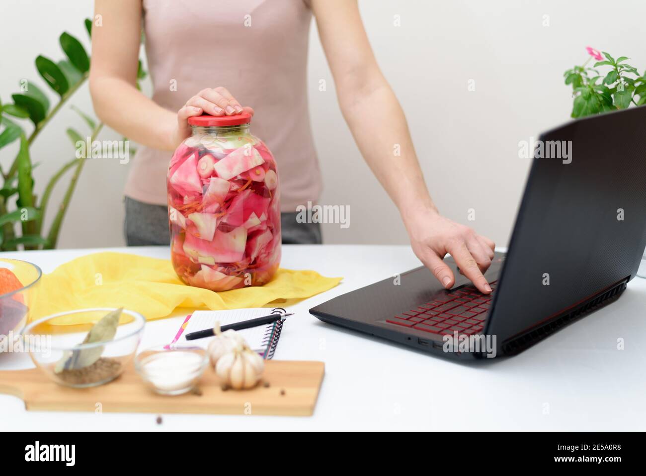 Cuisinez à la maison des recettes vidéo en ligne sur un ordinateur portable chou rose mariné fermentatif avec des betteraves et des carottes en saumure dans un pot. Banque D'Images