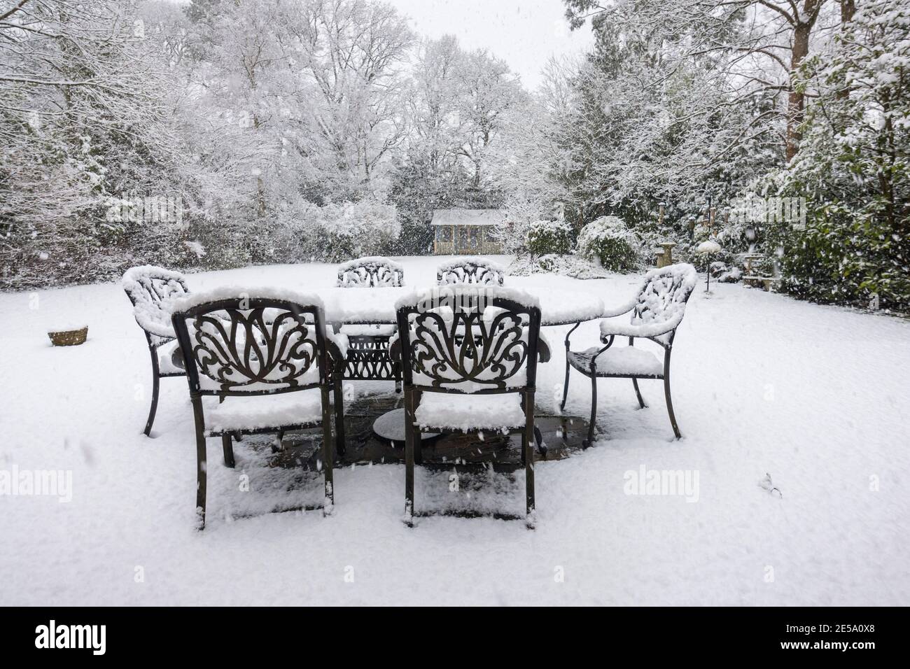 Tables et chaises extérieures sur un patio et arbres couverts de neige lors d'une forte chute de neige dans un jardin de banlieue Woking, Surrey, au sud-est de l'Angleterre Banque D'Images
