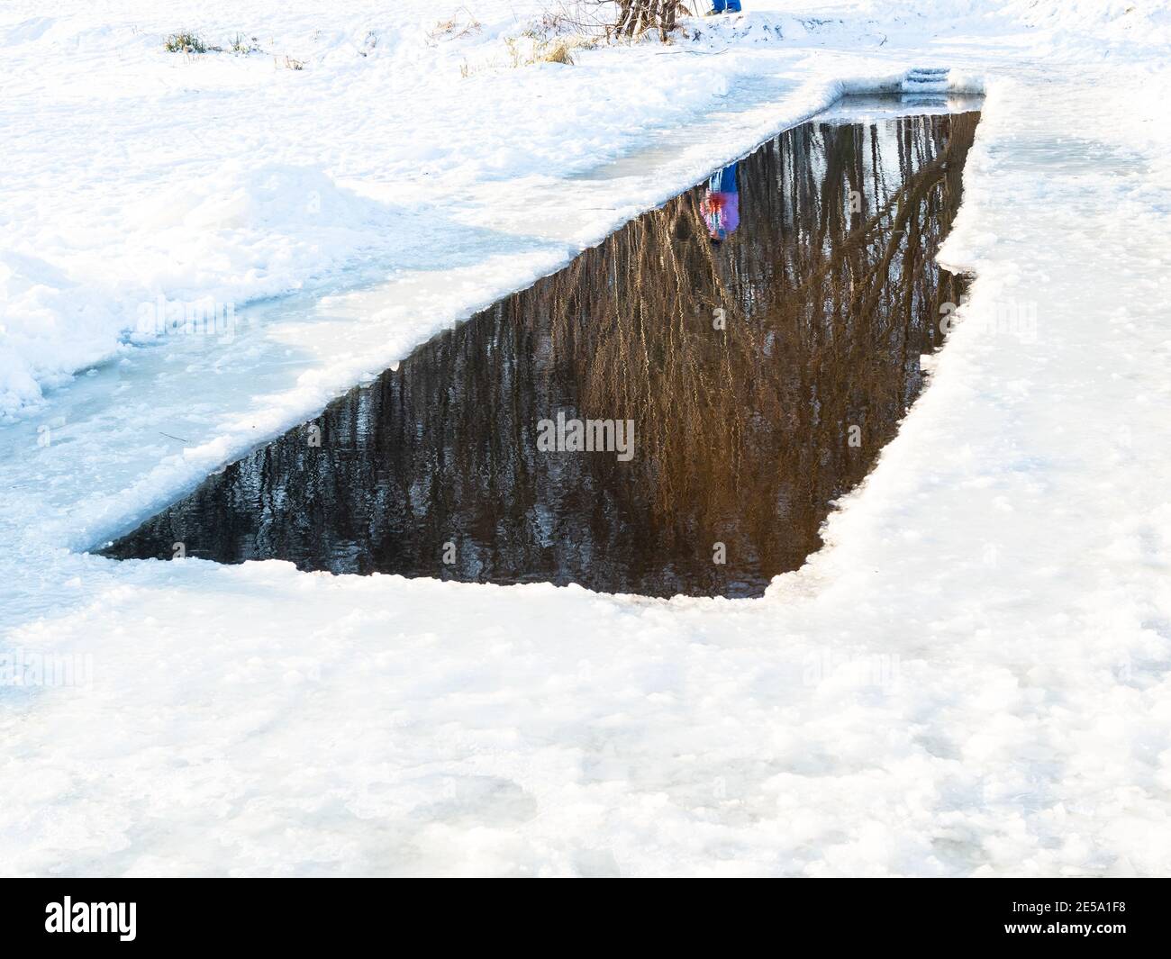baignade de la glace-trou dans l'étang gelé couvert de neige dans le parc de la ville sur froid ensoleillé jour de vin Banque D'Images