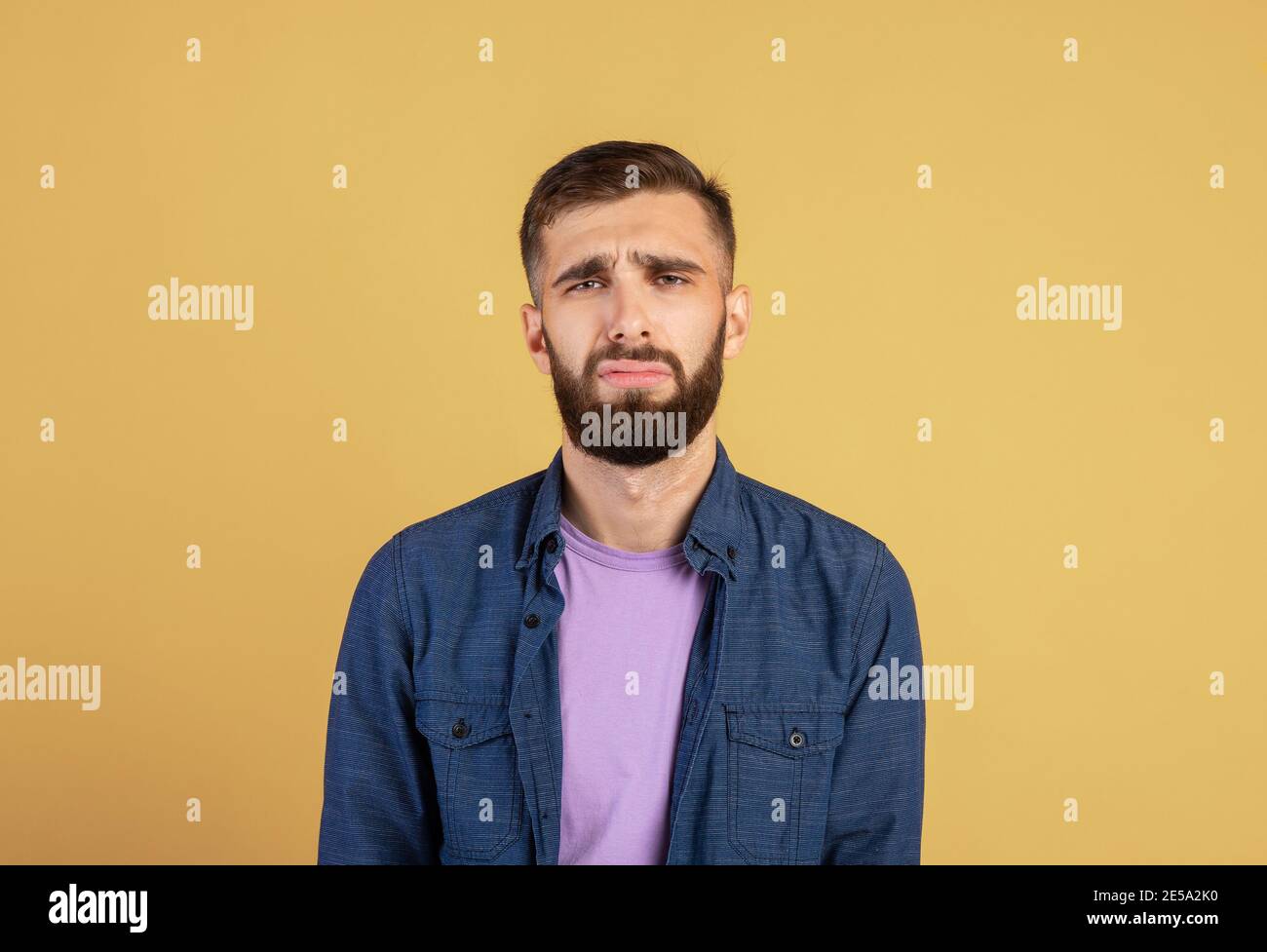 Jeune homme caucasien se sentant malheureux et déprimé, pleurant ou pleurant sur fond de studio couleur Banque D'Images