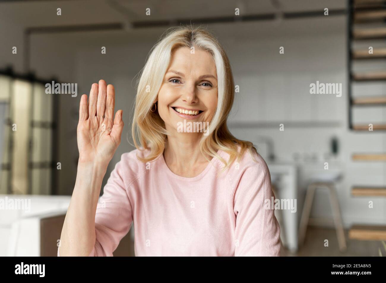 Webcam vue d'une charmante blonde femmes d'âge moyen ayant la vidéo  conférence, une femme joyeuse en agitant dans la caméra et sourires,  concept de réunion virtuelle Photo Stock - Alamy