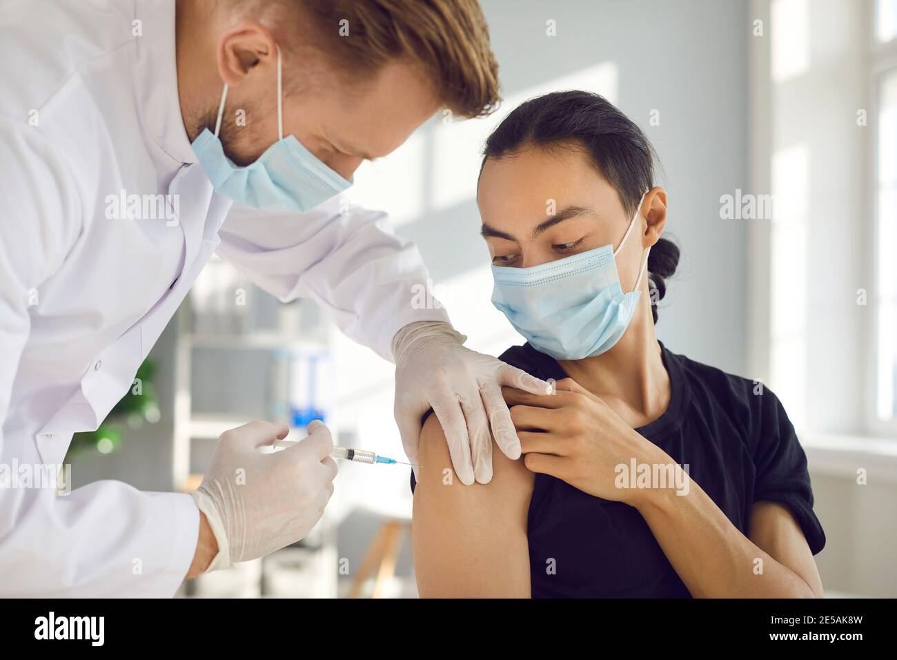 Le patient masculin dans le masque médical se fait la grippe saisonnière ou Le vaccin Covid-19 moderne Banque D'Images