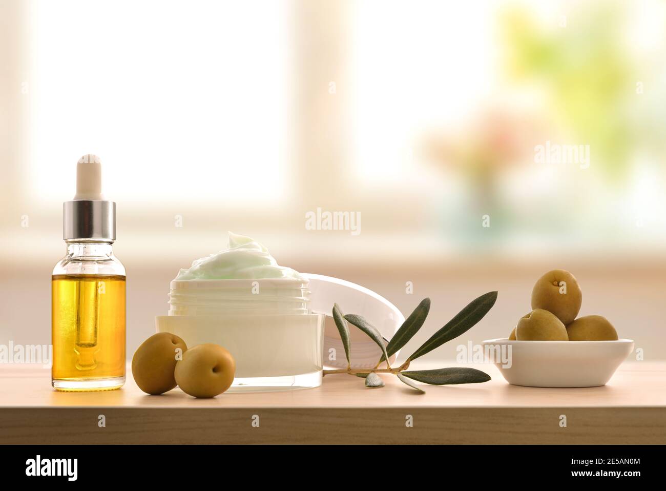 Sérum et crème cosmétique hydratante avec extrait d'olive pour la peau avec branche et olives sur table en bois. Vue avant. Banque D'Images