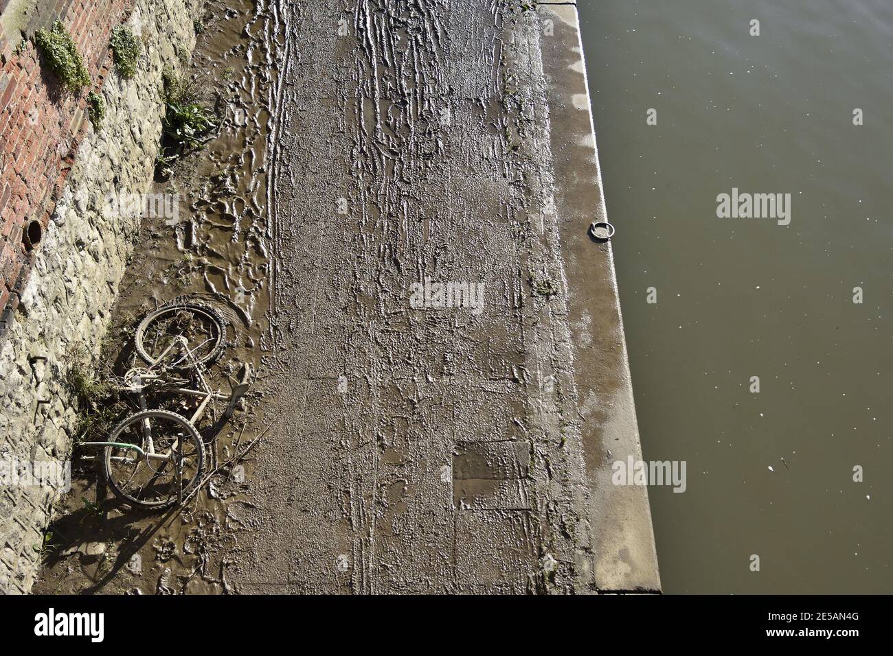 Maidstone, Kent, Royaume-Uni. Empreintes de pas, traces de pneus et une vieille bicyclette dans la boue épaisse laissée sur un sentier de basse altitude au bord de la rivière Medway, Banque D'Images