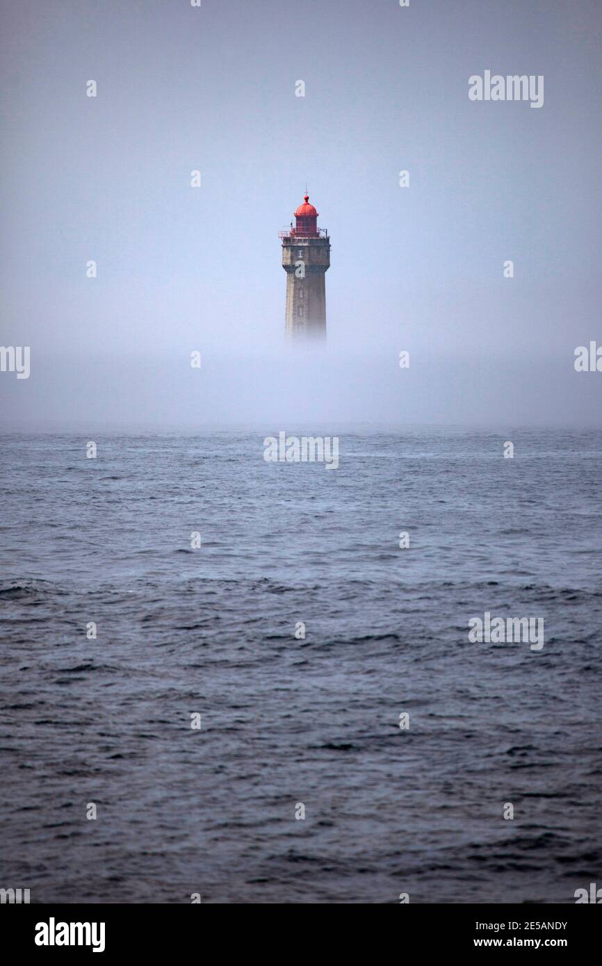 Le spectaculaire phare de la Jument, dans le brouillard estival, au large de l'Ile d'Ouessant, Bretagne. Le phare emblématique de 47 mètres de haut était bui Banque D'Images