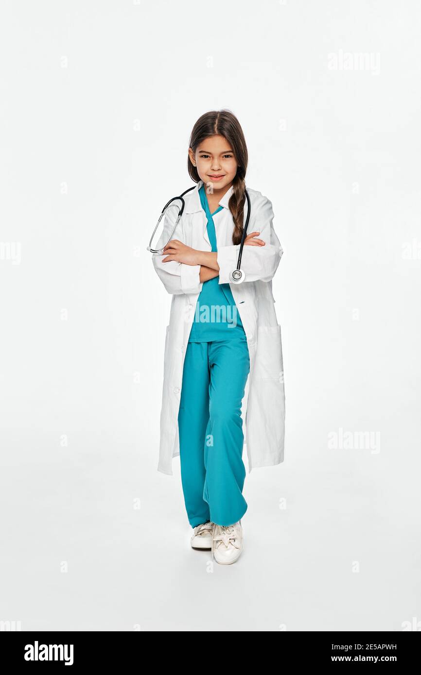 Enfant, futur médecin. Fille de race mixte portant un équipement médical avec un sourire crasseux, regardant l'appareil photo. Isolé sur fond blanc Banque D'Images