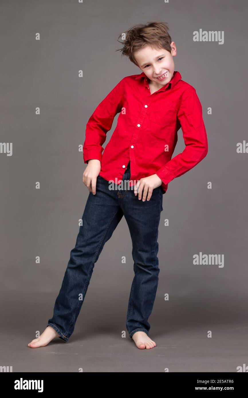 Beau garçon dans une chemise rouge et un Jean sur fond gris. Un enfant dans  le domaine de la modélisation pose Photo Stock - Alamy