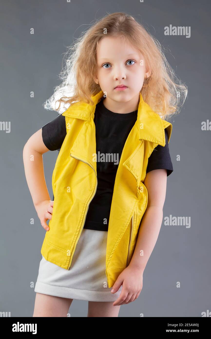 Belle petite fille blonde dans une veste jaune sur fond gris. Fille de cinq  ans. Modèles de tests pour un enfant Photo Stock - Alamy