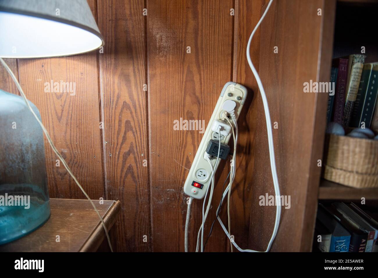 Un parasurtenseur avec de nombreux cordons branchés est monté sur le mur. Banque D'Images