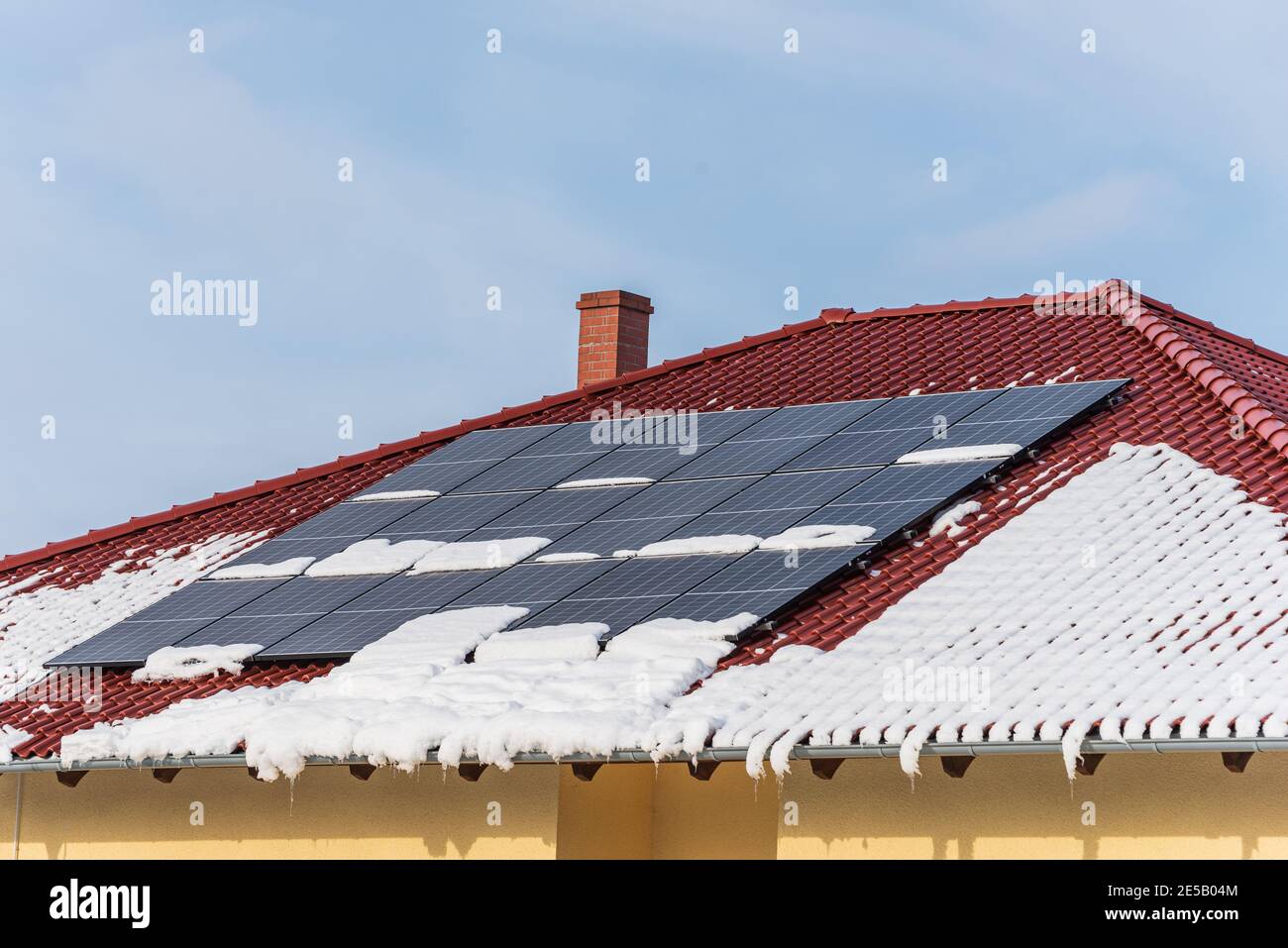 Toit de maison recouvert de panneaux solaires en hiver. L'électricité du soleil pendant l'hiver. Journée ensoleillée, ciel bleu et espace de copie. Banque D'Images