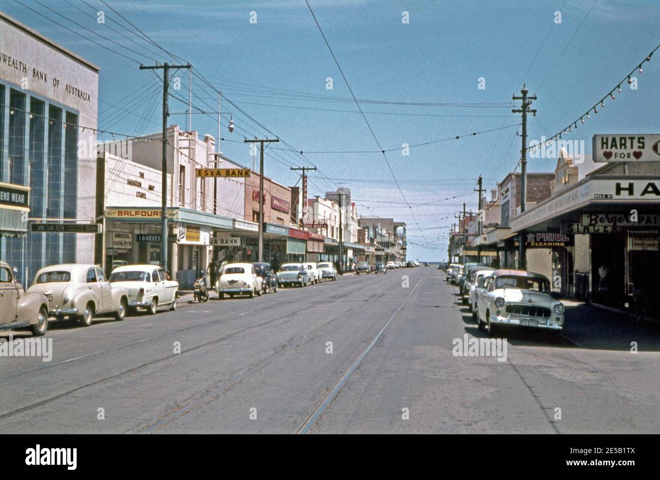 Magasins et entreprises le long de Jetty Road, Glenelg, Adélaïde, Australie méridionale, Australie en 1961. La rue est un grand quartier commerçant et fait presque 1 kilomètre de long. Cette vue est orientée vers l'ouest vers Moseley Square et le front de mer de Glenelg. La ligne de tramway Glenelg longe la route et relie la plage de Glenelg à la ville d'Adélaïde. Banque D'Images