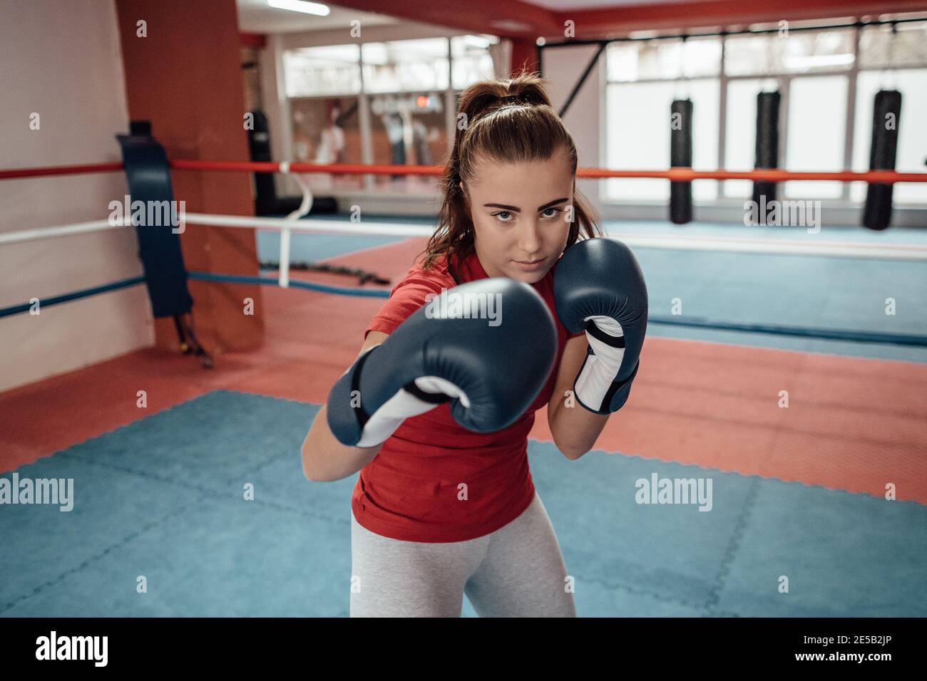 Gros plan d'une jeune boxeur de boxe féminine avec des gants de boxe pointant vers l'appareil photo. Une fille kickboxing dans un anneau de boxe. Banque D'Images