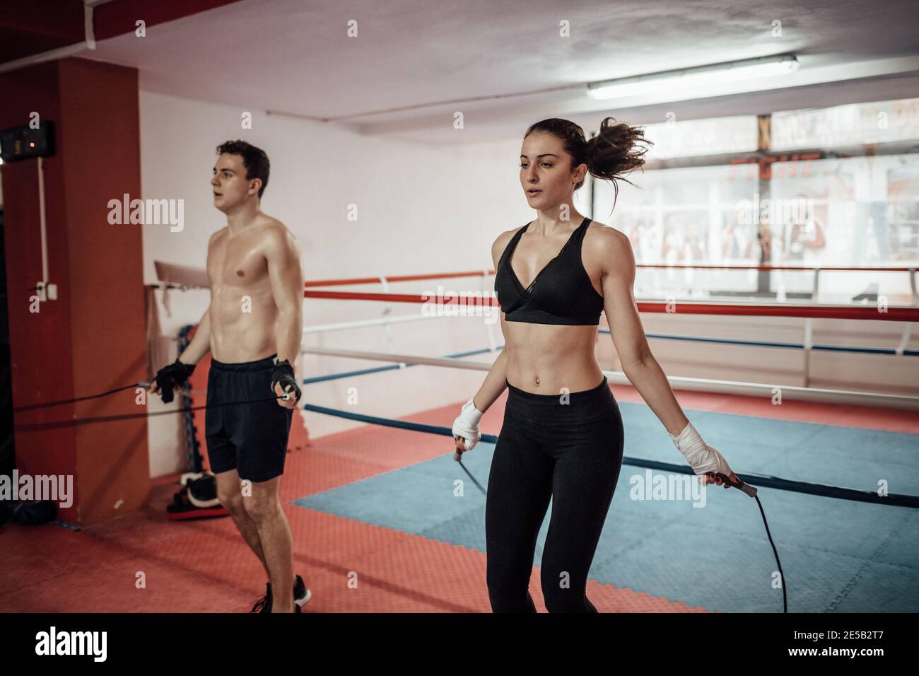 Un homme et une femme sautent ensemble dans un club sportif. Un couple s'entraînant avec une corde à sauter dans une salle de gym. Banque D'Images