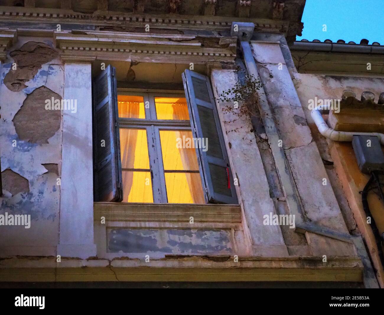Chambre éclairée avec fenêtres en bois dans le vieux bâtiment le soir, Nafplio, Grèce Banque D'Images
