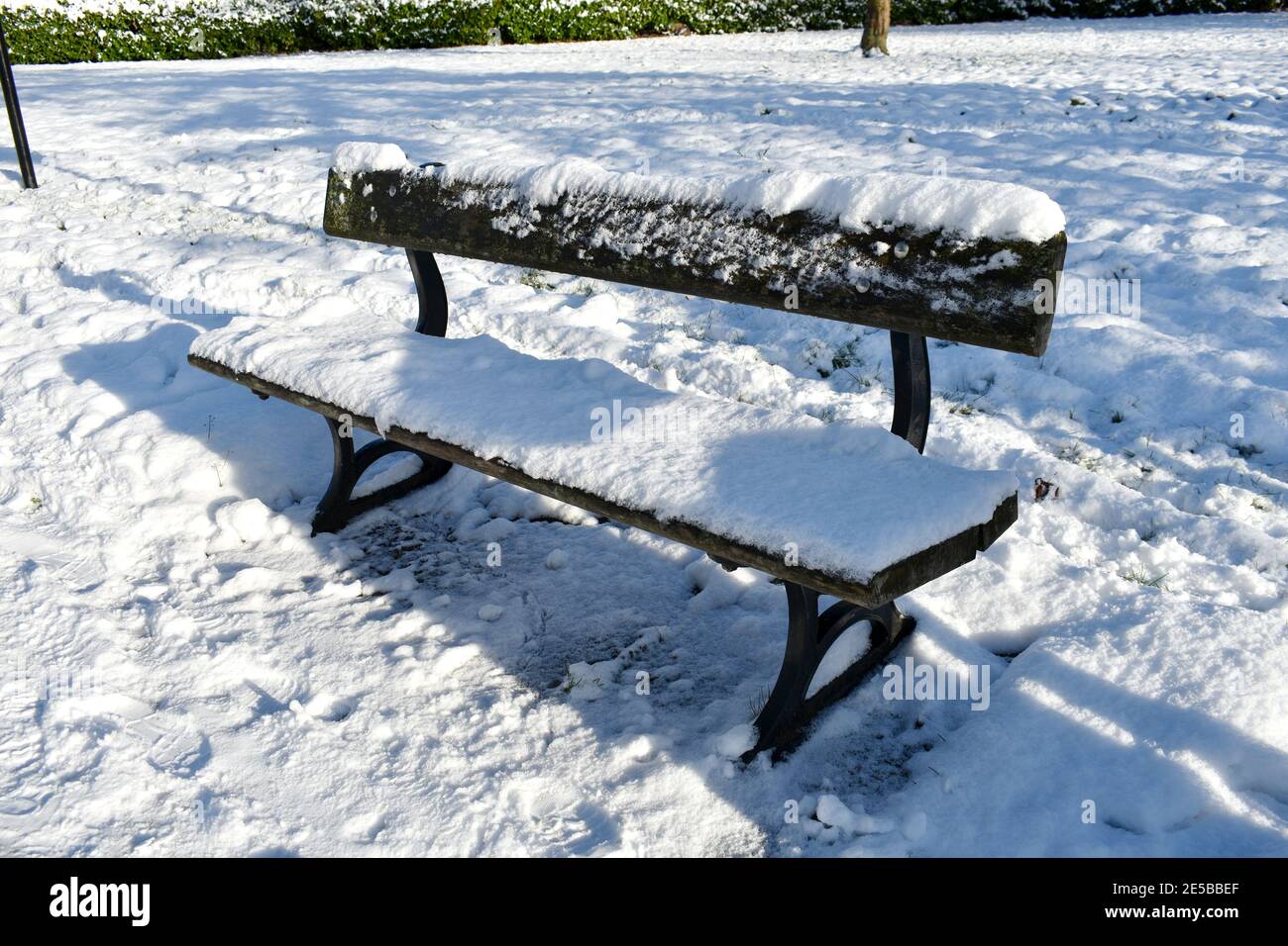 gros plan sur un banc de parc en bois vide recouvert de neige à la suite d'une chute de neige profonde. à l'extérieur, par temps ensoleillé et froid Banque D'Images