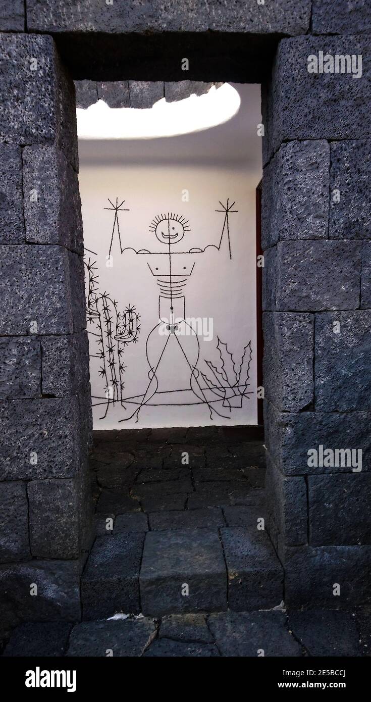 Panneau de toilettes publiques illuminé inhabituel menant à un homme w.c. Lanzarote, Canaries, Iles, Espagne. Le bâtiment est construit de blocs de lave. Banque D'Images