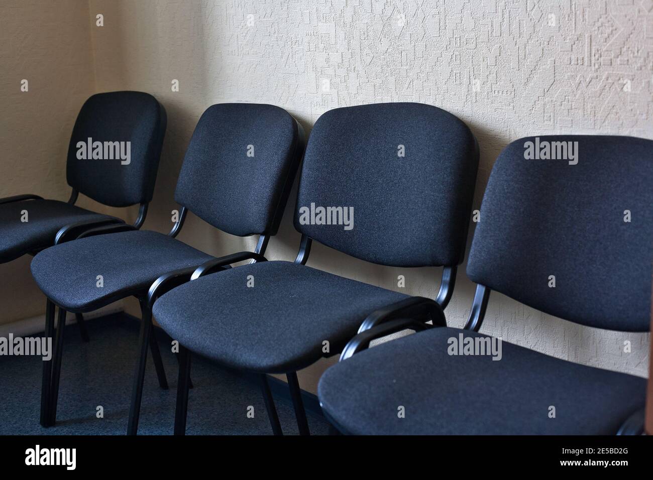 Les chaises de bureau en tissu noir sont alignées le long du mur. Banque D'Images