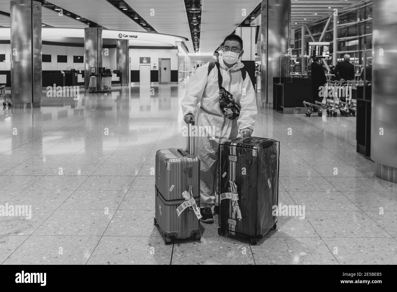 Un touriste arrive d'Asie dans UN costume de protection contre les matières dangereuses jetable à l'aéroport de Heathrow pendant la pandémie Covid 19, Londres, Royaume-Uni. Banque D'Images