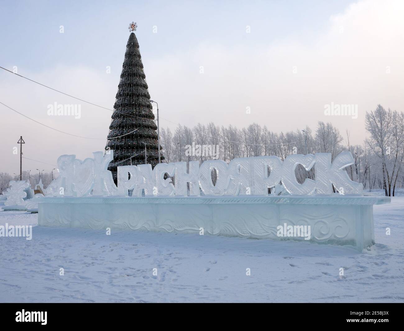 Le nom de la ville en russe sculpté dans la glace se dresse sur le fond d'un arbre de Noël décoré avec les armoiries de la ville. Banque D'Images