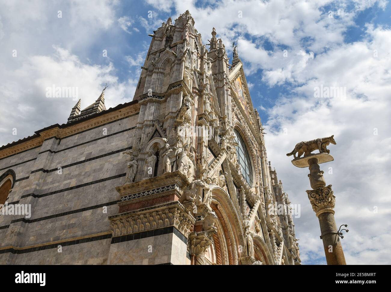 Côté gauche de la cathédrale de Sienne (Sainte Marie de l'Assomption) de style roman-gothique avec le loup siennois sur une colonne, Toscane, Italie Banque D'Images