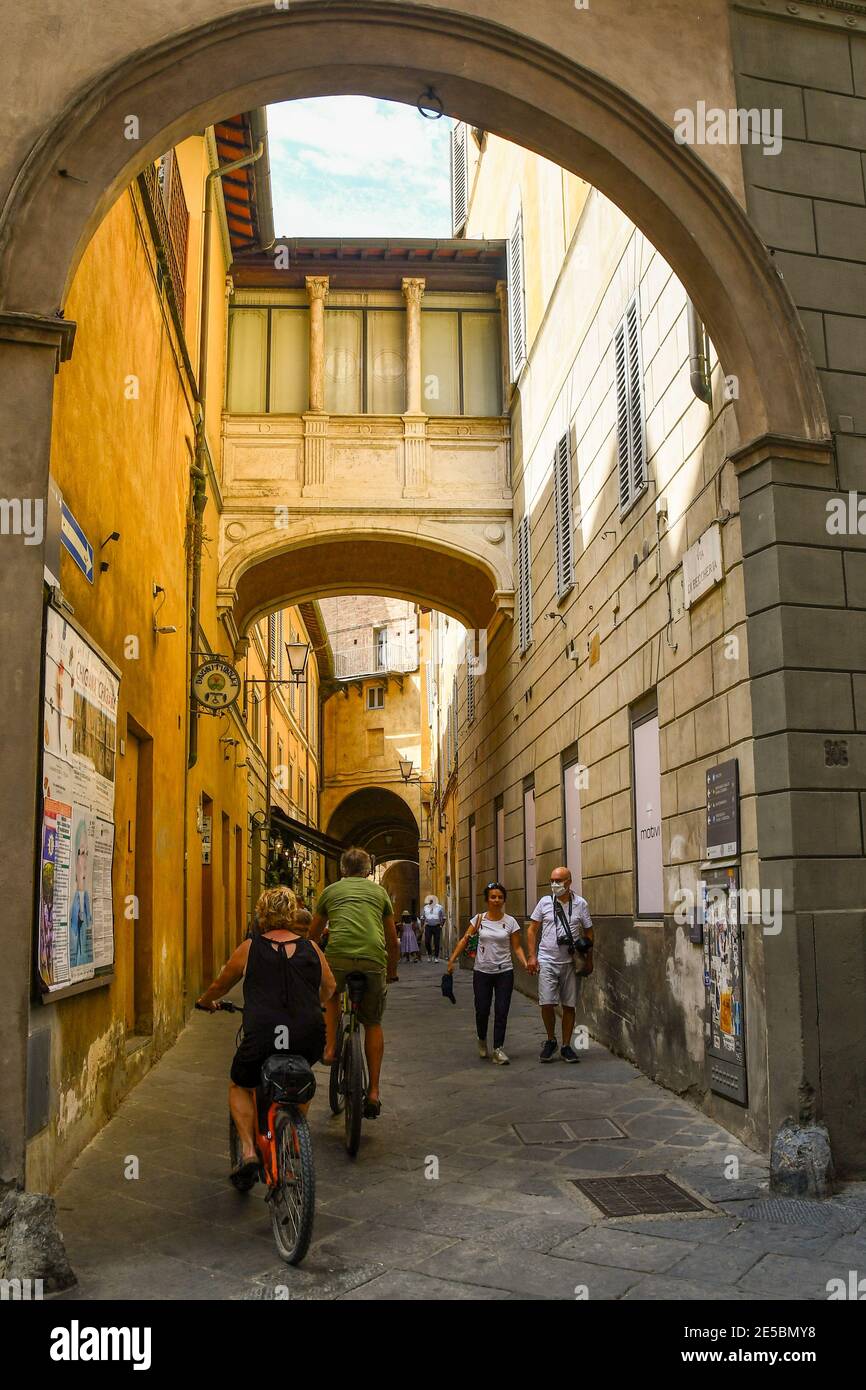 Via di Beccheria dans le centre historique de Sienne, site classé au patrimoine mondial de l'UNESCO, avec des gens et des touristes marchant et faisant du vélo en été, Toscane, Italie Banque D'Images