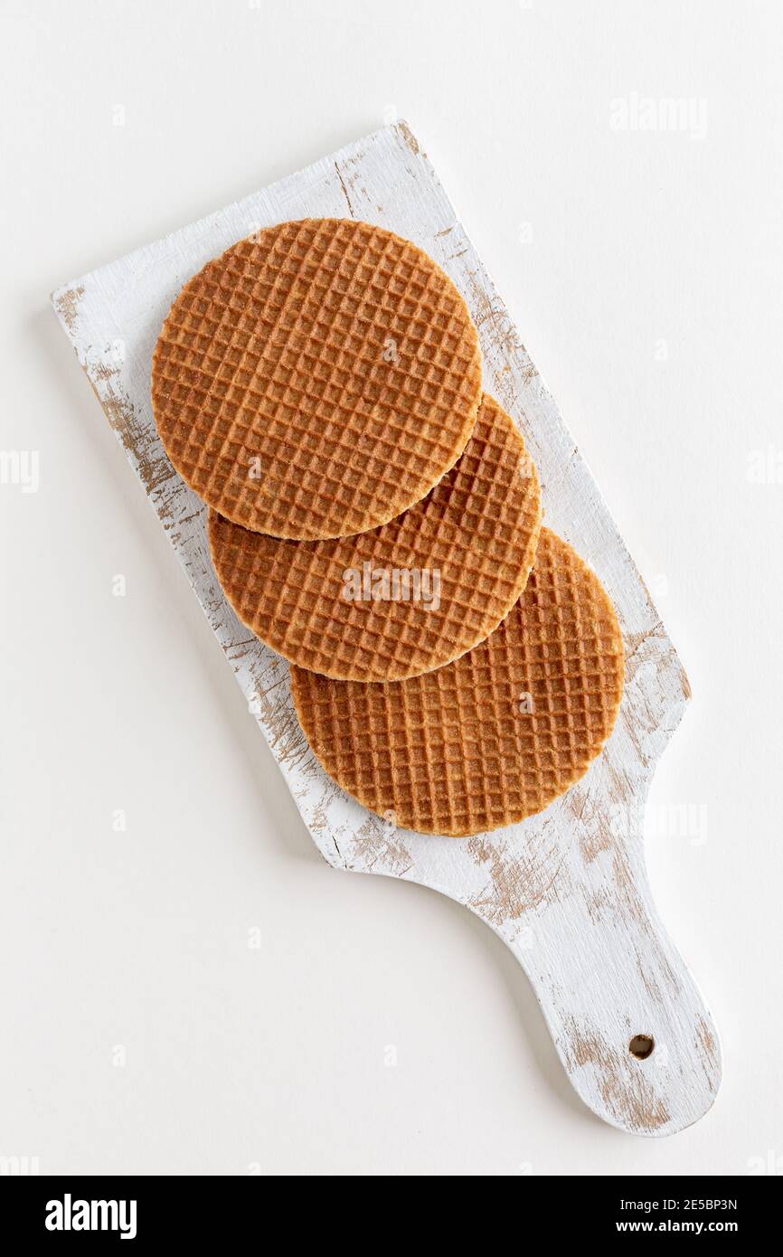 Vue de dessus de trois stropwafels hollandais traditionnels (sirop ou gaufres au caramel) sur un tableau blanc sur fond blanc, espace de copie Banque D'Images