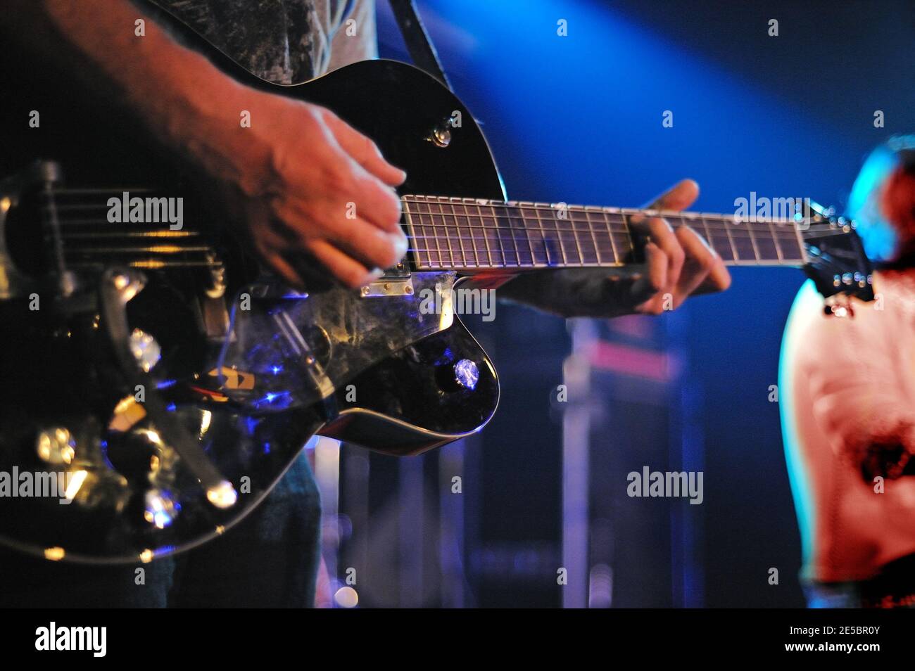 Gros plan au musicien jouant de la guitare sur scène éclairé par une lumière bleue. Banque D'Images