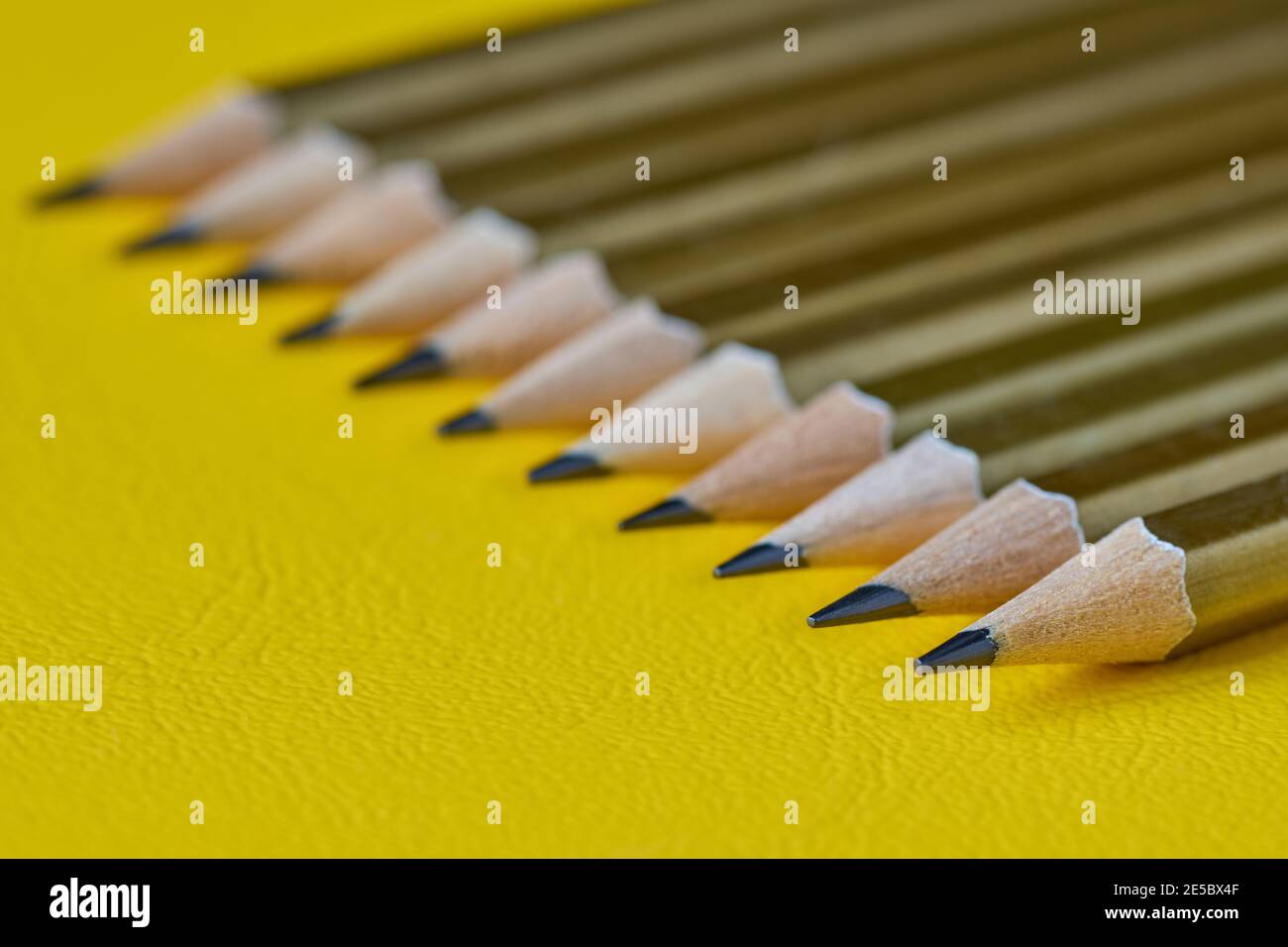 Rangée de crayons simples sur fond jaune, faible profondeur de champ Banque D'Images