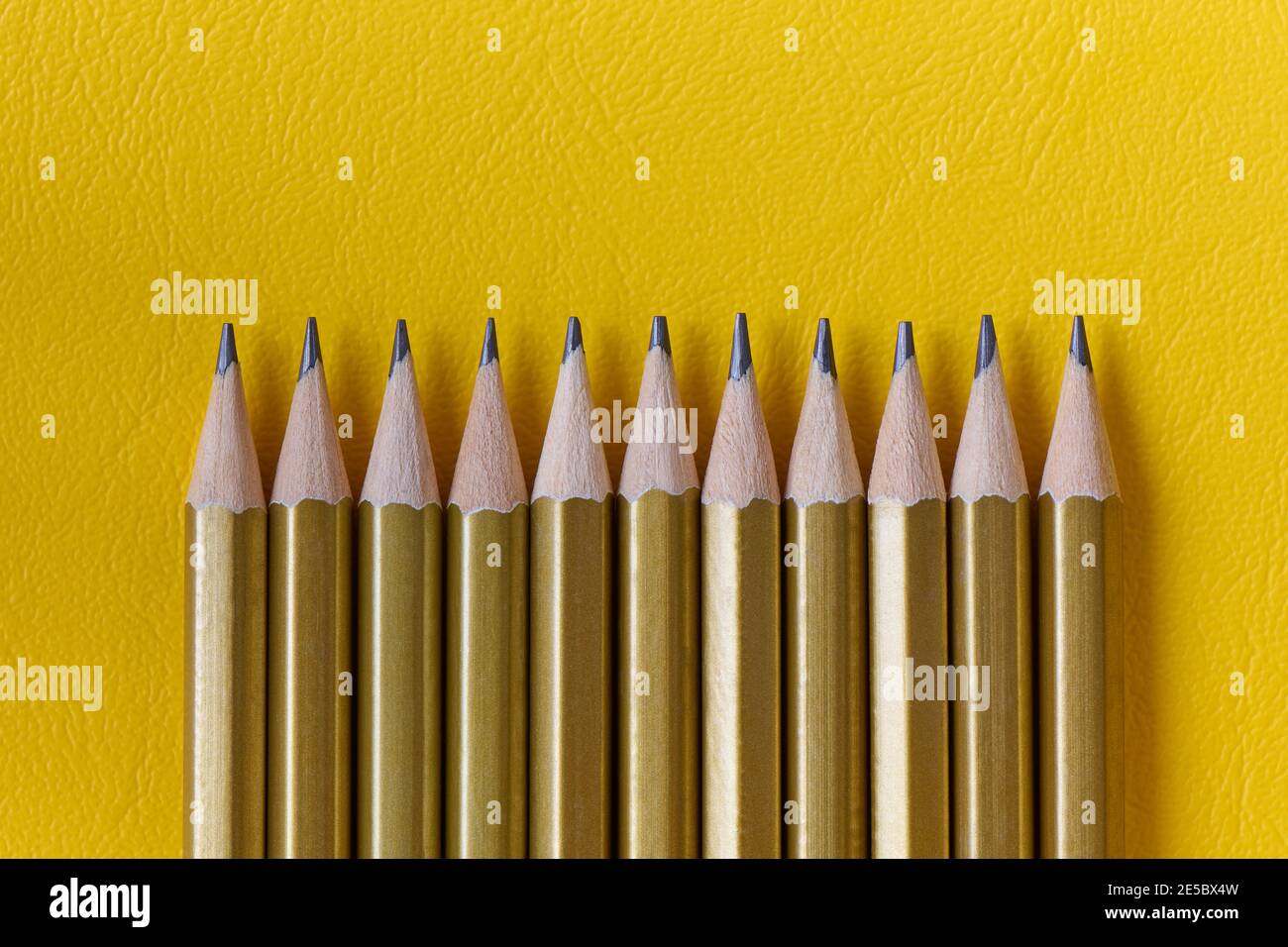 Ligne de crayons ordinaires sur fond jaune avec espace de copie, plan plat, gros plan Banque D'Images