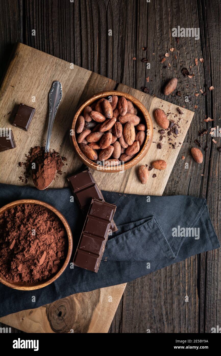 En-cas sain, superfood fèves de cacao non grillées dans un bol en bois décoré de cacao en poudre Banque D'Images