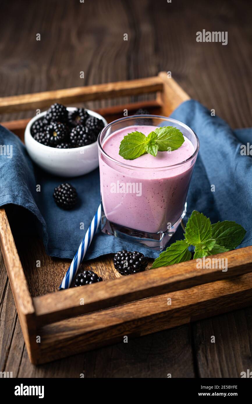 Boisson laitière sucrée, milkshake de mûre dans un verre sur un fond en bois Banque D'Images