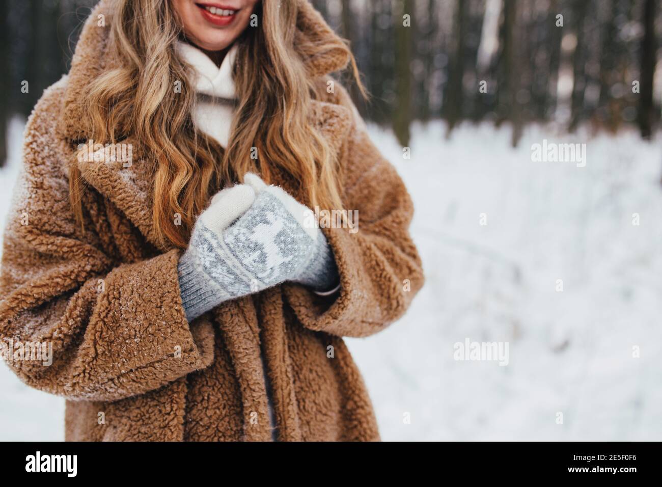 Jeune femme en fourrure, gants et foulard dans une forêt enneigée. Arrière-plan flou Banque D'Images
