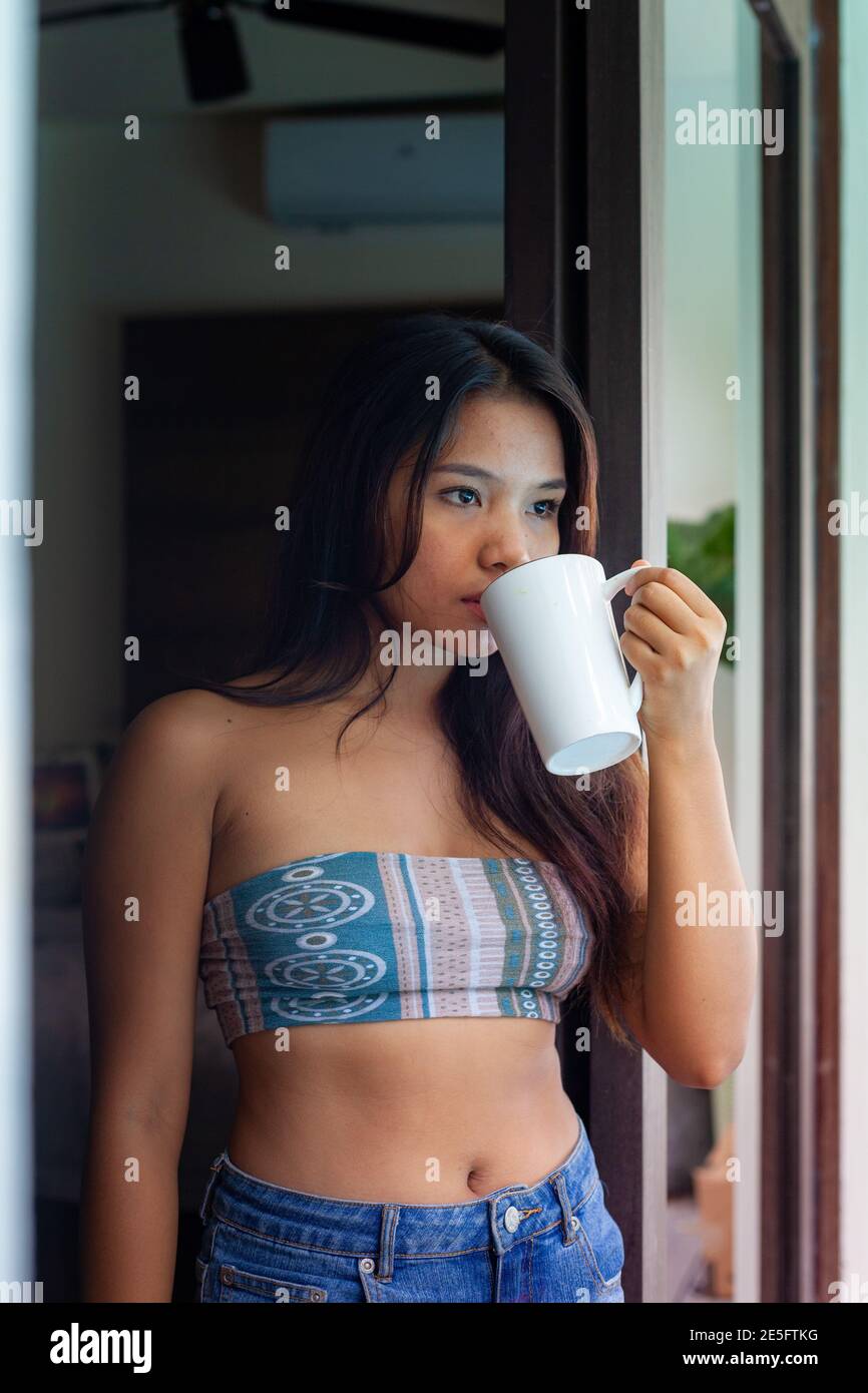 Asiatique jeune et mignonne fille heureuse d'avoir un café parfumé le matin à la maison, la villa ou le Resort Banque D'Images