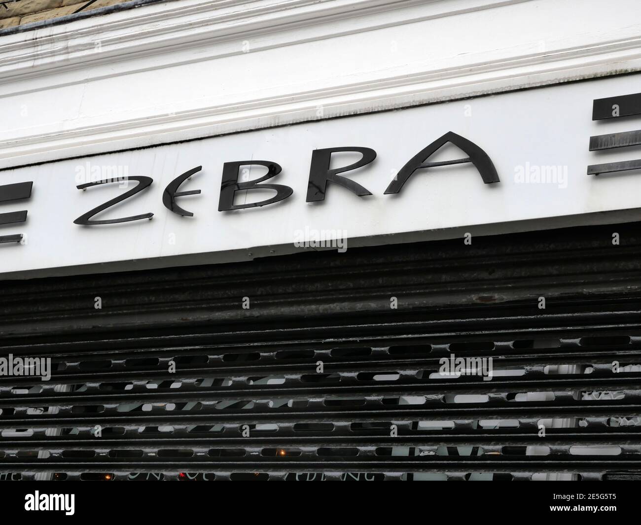 Affiche Zebra sur le devant du magasin, lettres noires sur fond blanc sur des volets noirs Banque D'Images