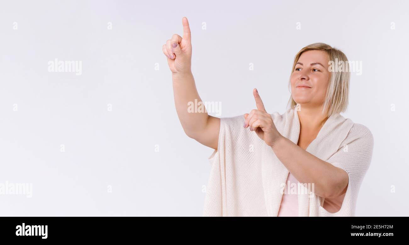 Bannière,format long. La femme plus âgée pointe ses index vers le haut. Fond blanc et espace publicitaire vierge. Banque D'Images