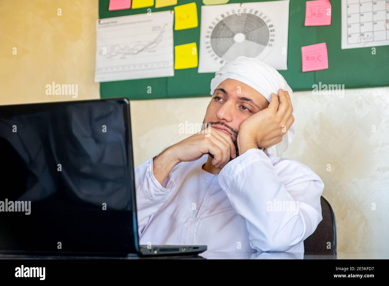 le jeune arabe pense dans son travail avec un regard sérieux sur son visage devant cet ordinateur portable Banque D'Images