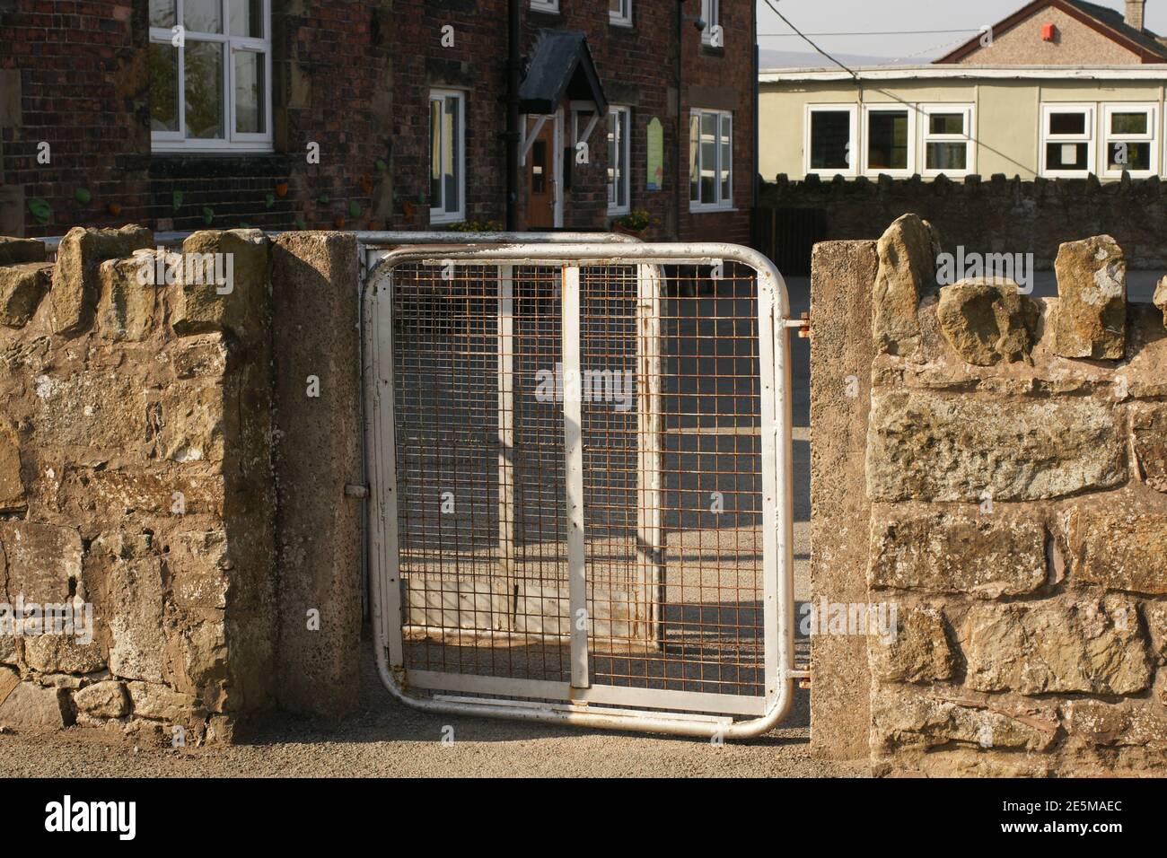 Les portes de l'école primaire sont fermées et un terrain de jeu vide à a École rurale au nord du pays de Galles au Royaume-Uni Banque D'Images