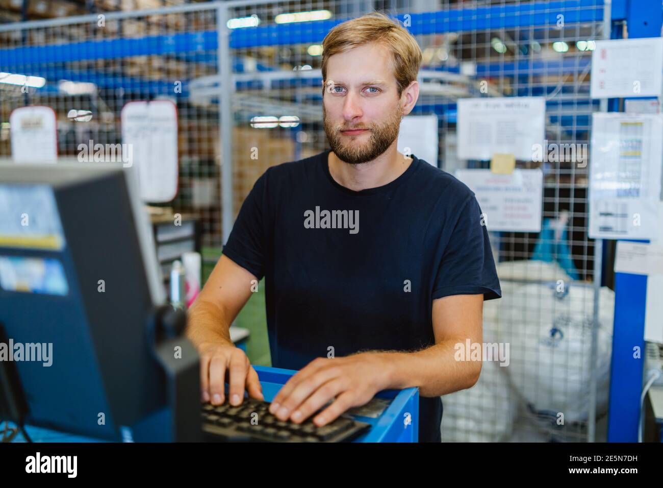 préparateur de commande de 30 ans fonctionnant sur un ordinateur à l'entrepôt Banque D'Images