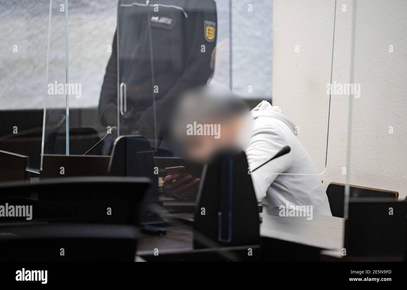 Stuttgart, Allemagne. 28 janvier 2021. Le défendeur, dans un procès pour meurtre, siège sur un banc au tribunal régional de Stuttgart. L'accusation est convaincue que l'homme a poignardé sa femme, qui avait dix ans de moins que lui, à mort dans la rue ouverte de Stuttgart l'année dernière parce qu'elle voulait se séparer de lui. Credit: Marijan Murat/dpa - ATTENTION: Personne(s) ont été pixelated pour des raisons juridiques/dpa/Alamy Live News Banque D'Images