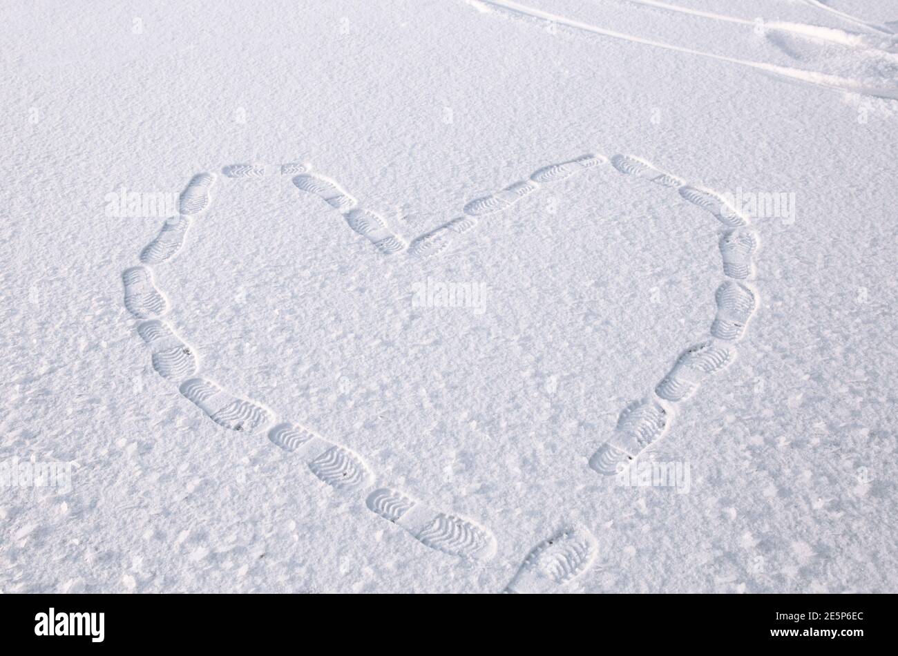 dessin symbolique d'un coeur sur la neige, fait par les marches des pieds. Empreintes de pas dans la neige. Concept de la Saint-Valentin, symbole d'amour. Marche entertai Banque D'Images