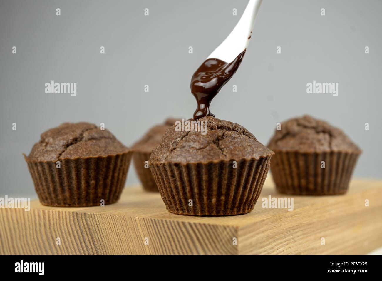 Verser le chocolat fondu dans les muffins au chocolat sur une planche en bois Banque D'Images