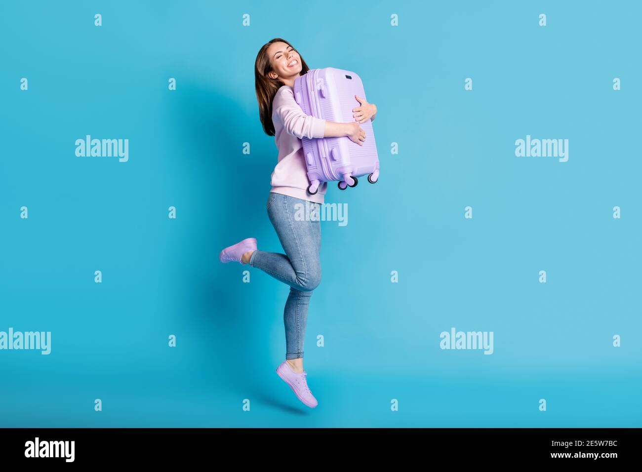 Pleine photo de gaie fille de saut touristique la hug valise profiter de voyage aéroport de quitter les frontières ouvertes porter violet lilas jeans en denim Banque D'Images