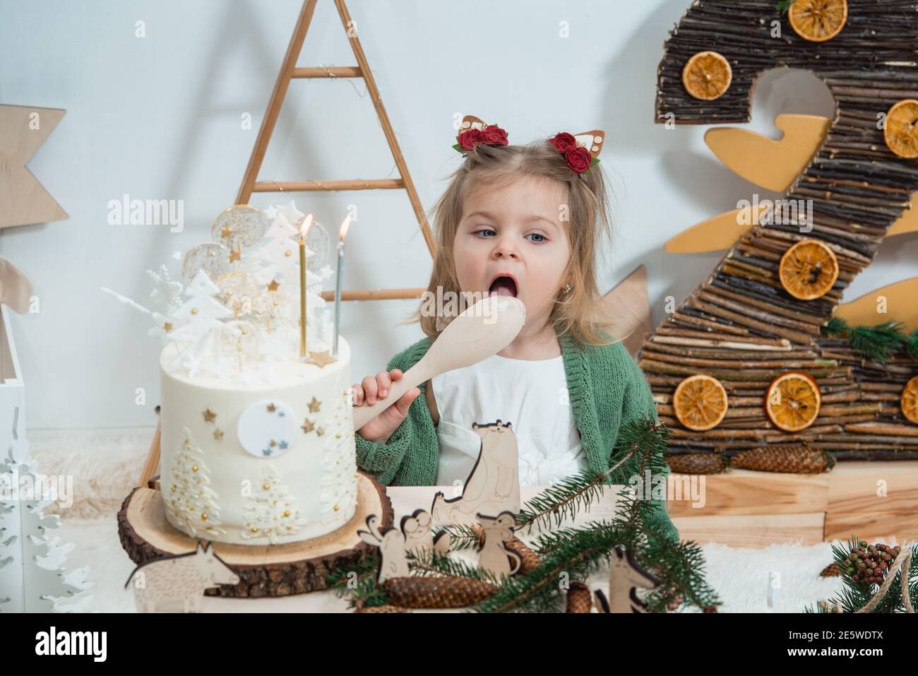 Decorations D Anniversaire D Hiver Pour Enfants 2 Ans Jolie Petite Fille Dans Un Gilet Vert Pres D Un Gateau D Anniversaire Blanc Photo Stock Alamy