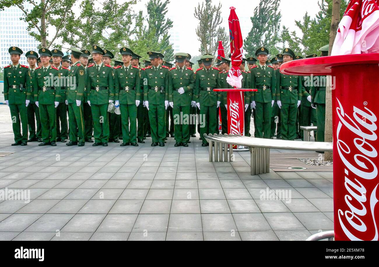 Les soldats de Chines se préparer à la marche entourée de panneaux Coca-Cola Banque D'Images